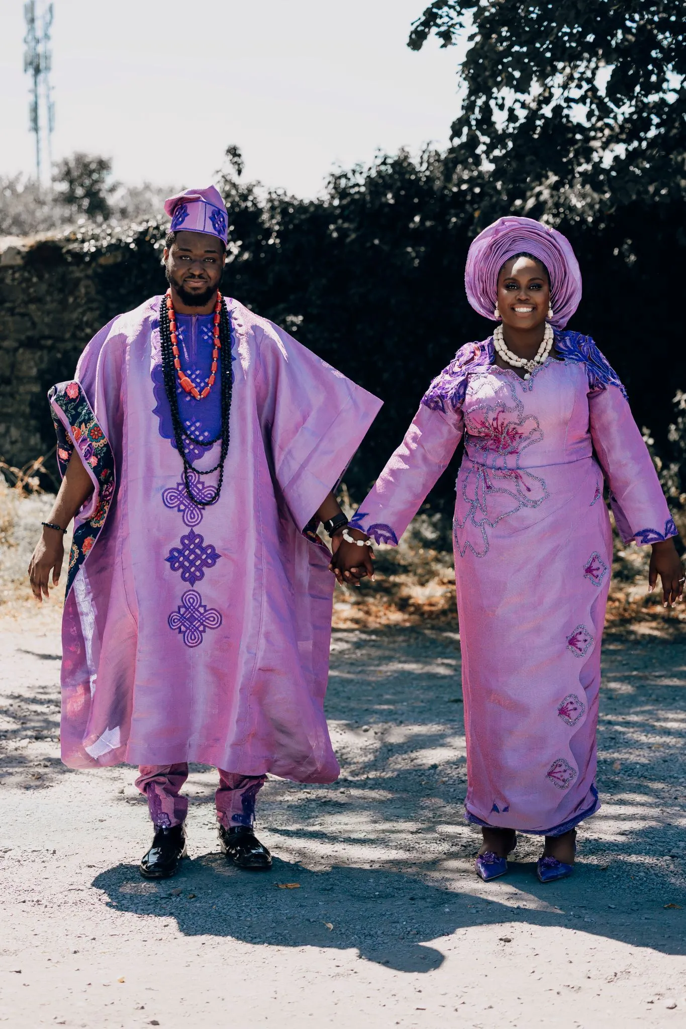 Couple in traditional purple attire holding hands outdoors.