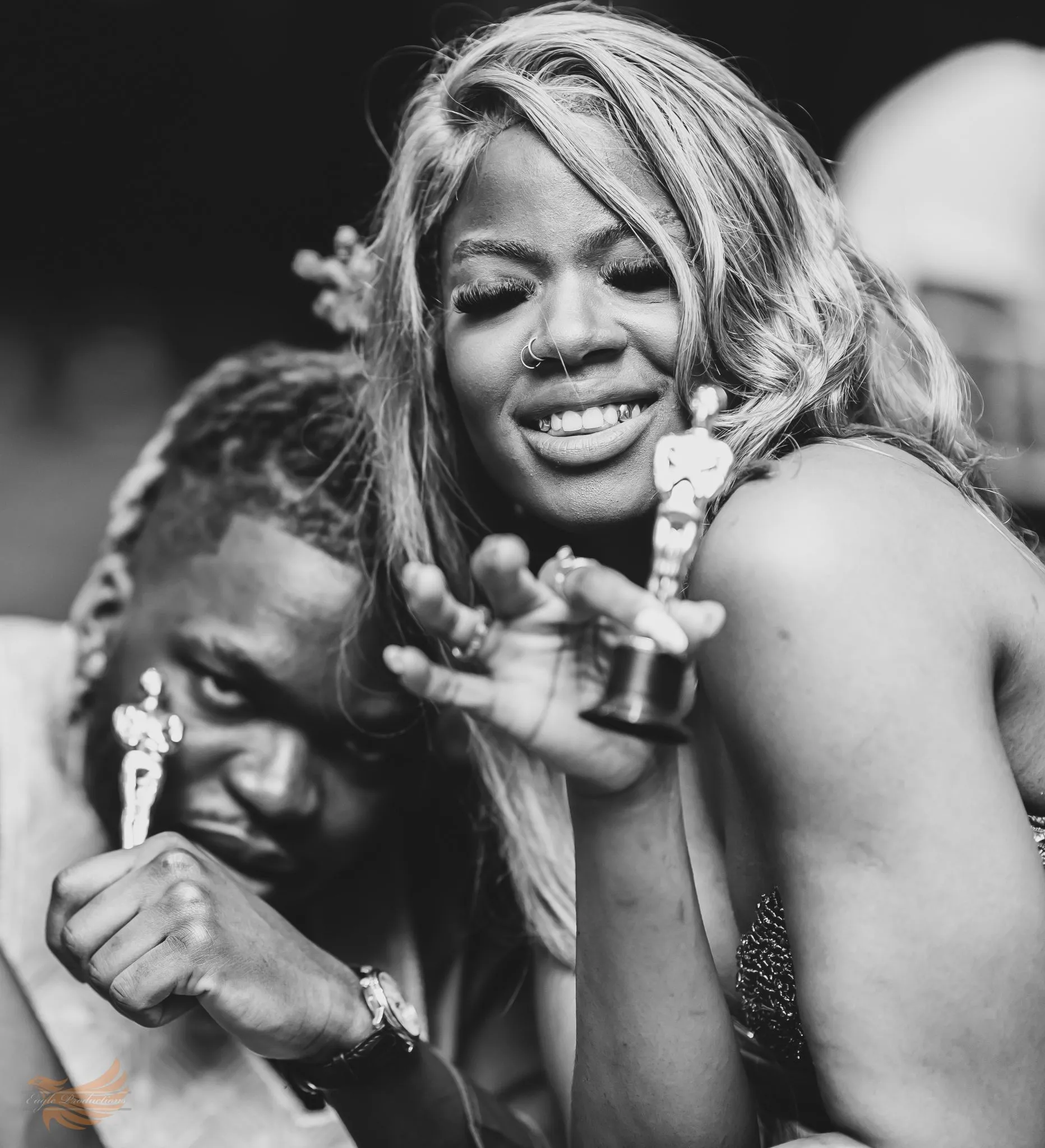 Two people celebrating with awards, smiling joyfully.