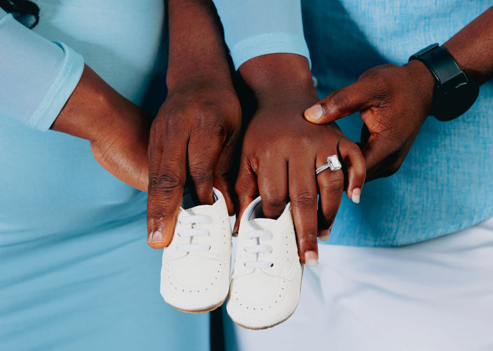 Family holding baby shoes together, symbolizing new beginnings.