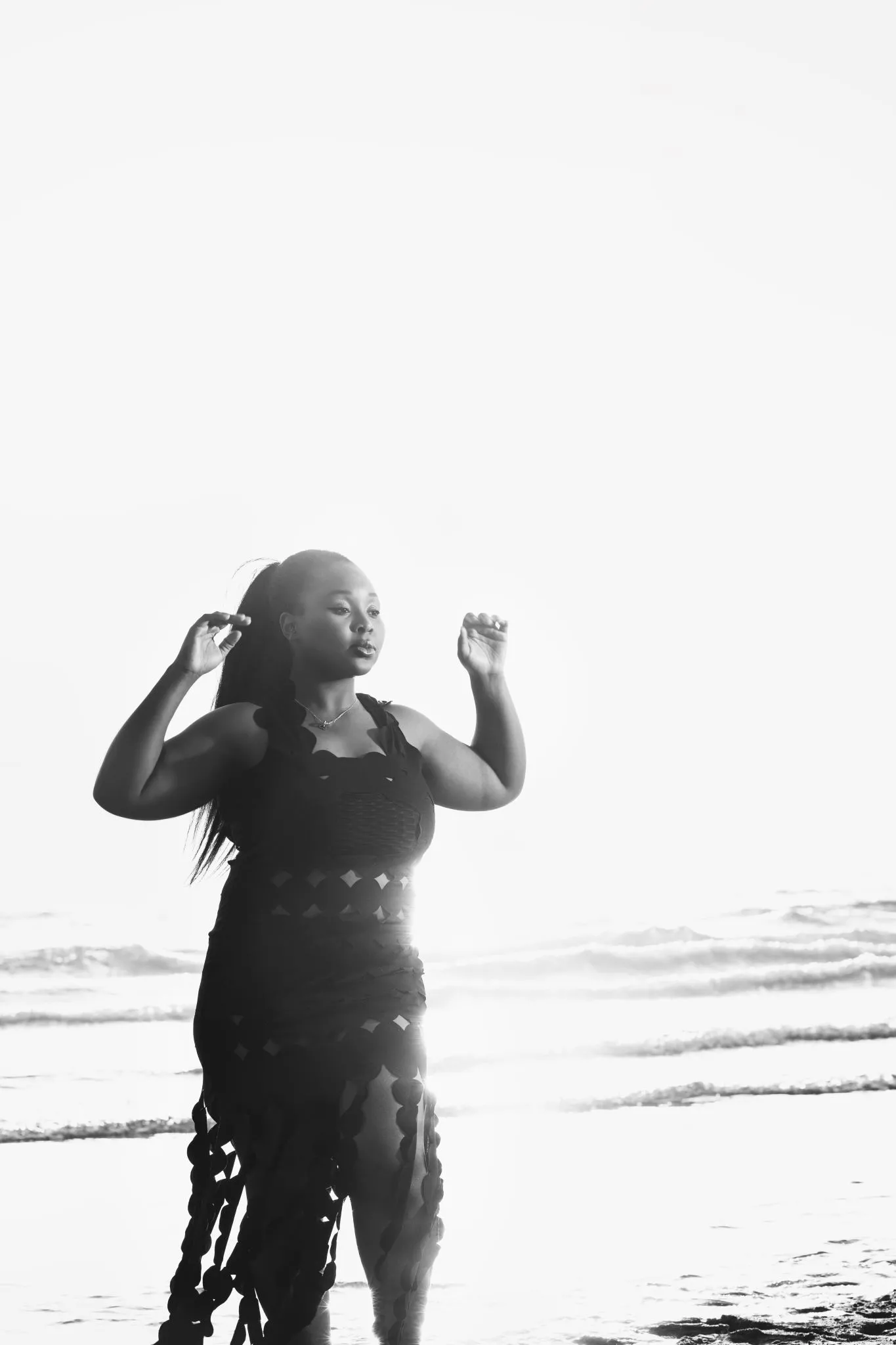 Woman in a stylish dress standing on a sunny beach