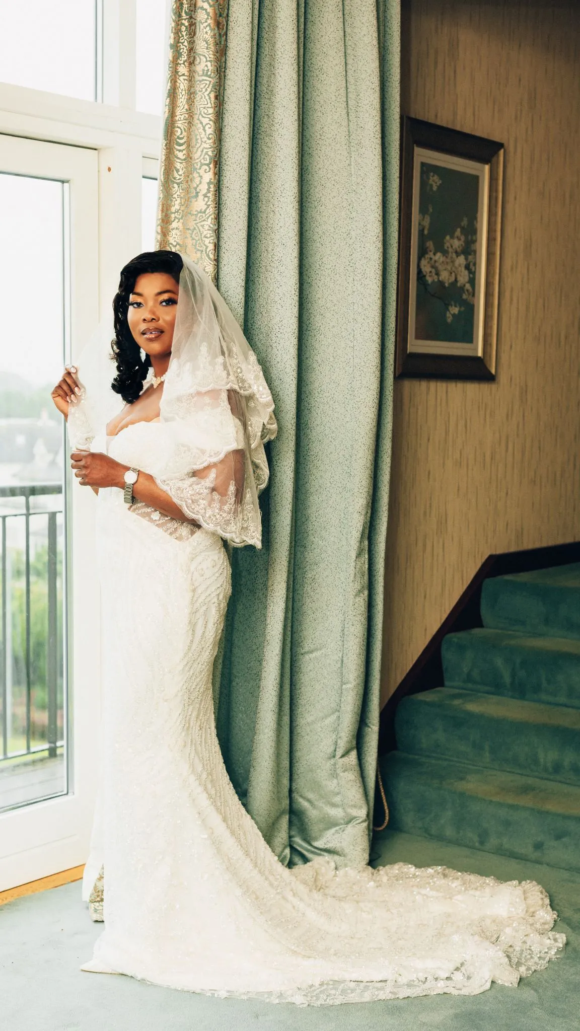 Bride in elegant wedding dress standing by a window