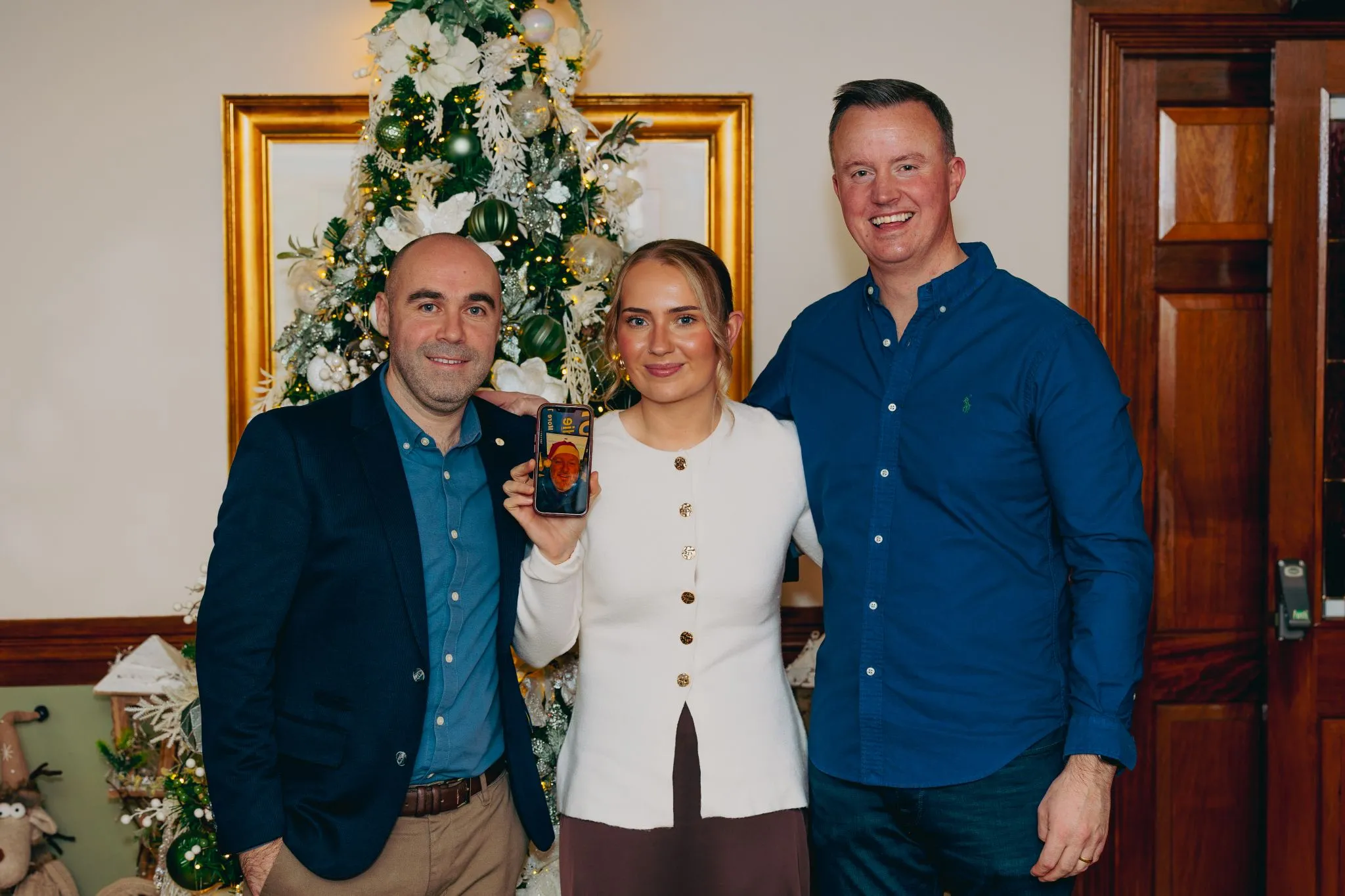 Group celebrating Christmas in front of a decorated tree.
