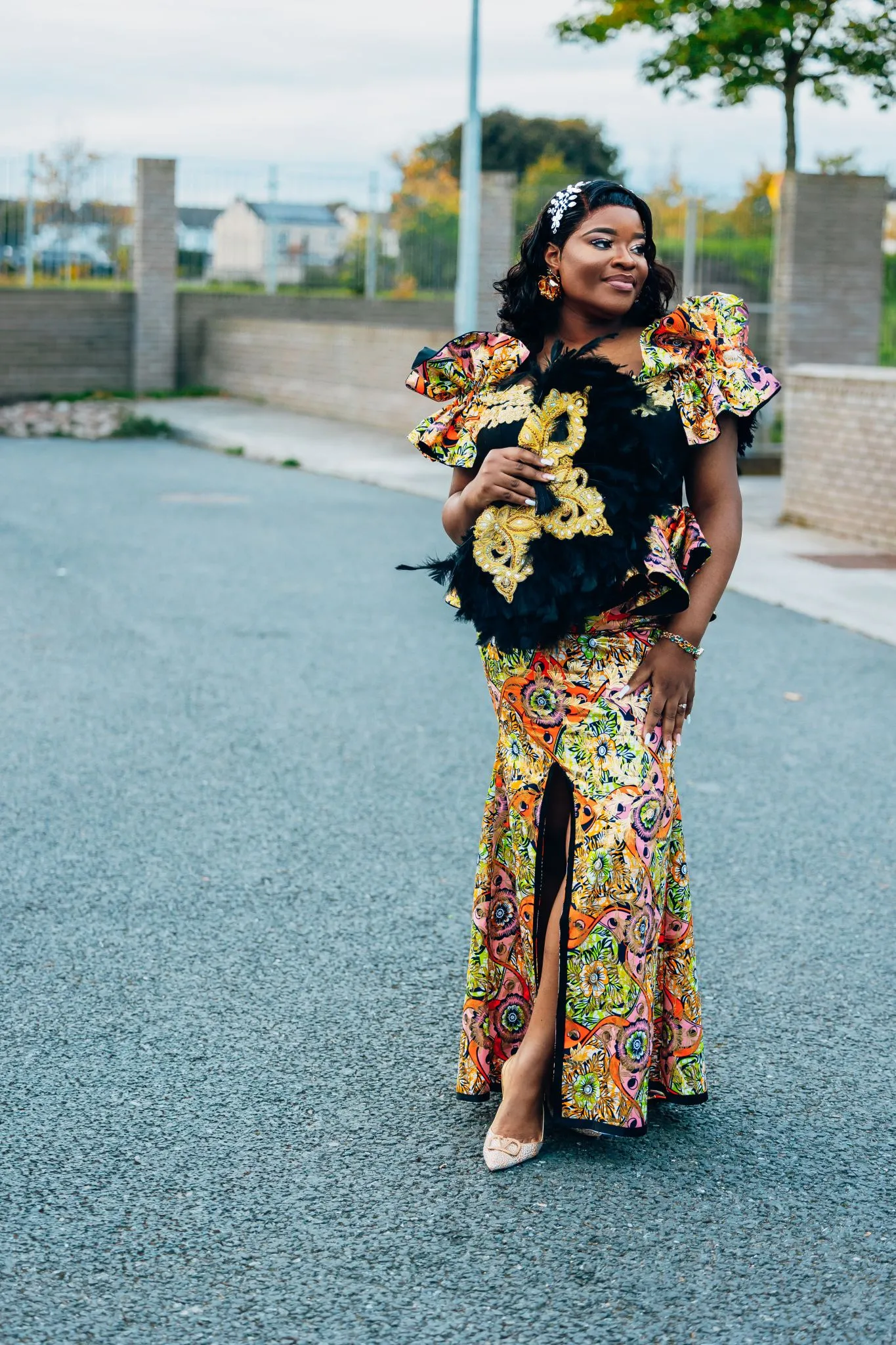 Woman in a colorful African dress with vibrant patterns and ruffled sleeves.