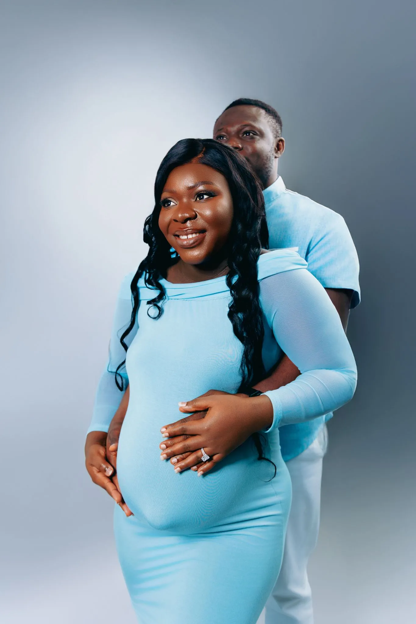 Happy couple in blue embracing during maternity portrait