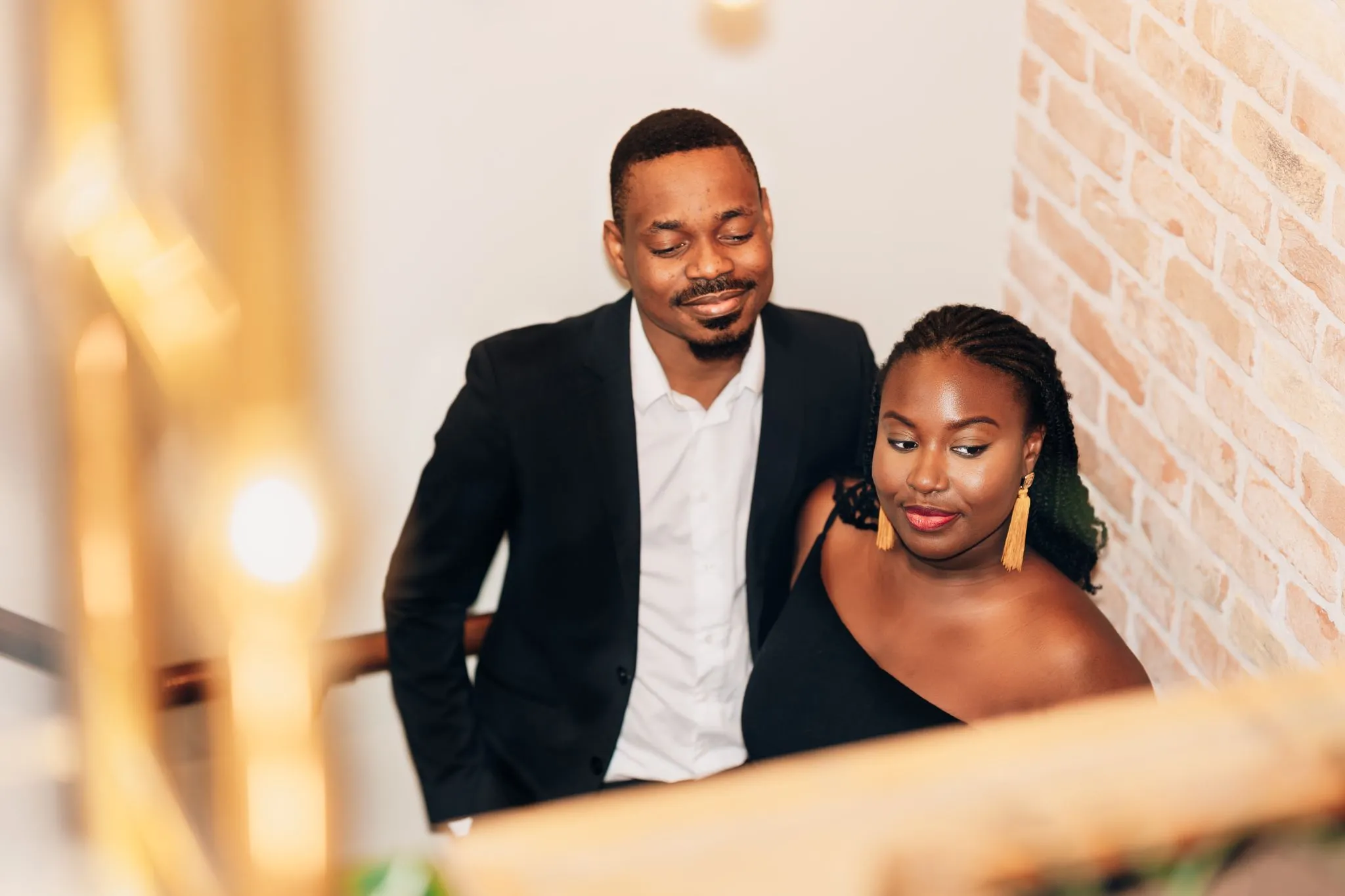 Smiling couple on staircase, dressed elegantly.