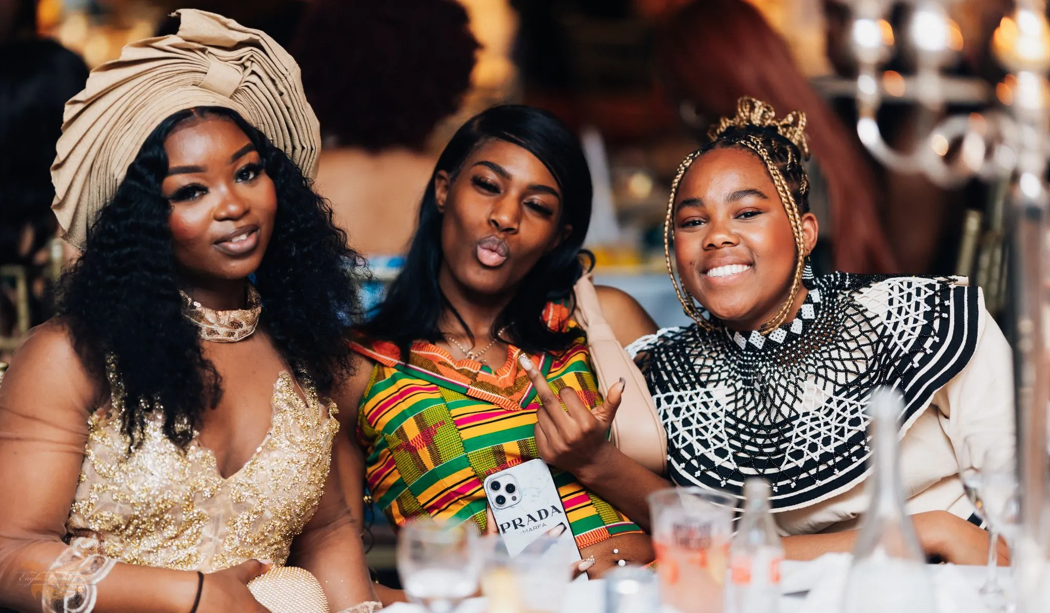 Three women in vibrant cultural attire at a celebration event.