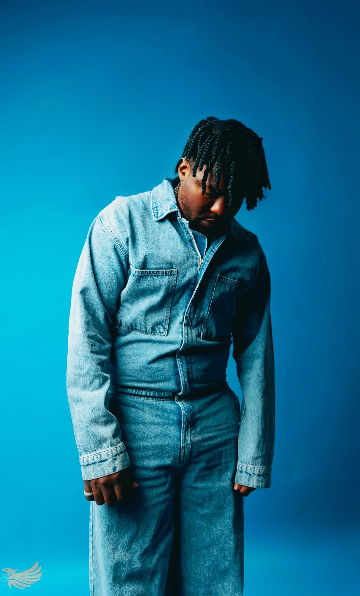 Person in denim outfit posing against a blue background