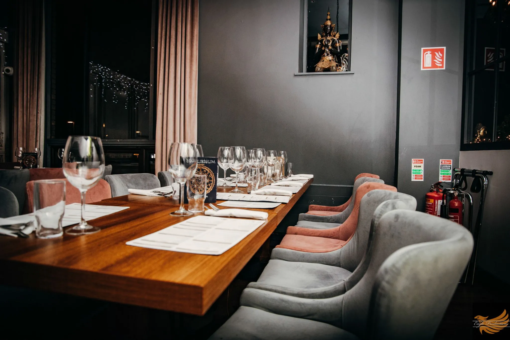 Elegant dining setup with a long wooden table and plush chairs at Eagle restaurant.