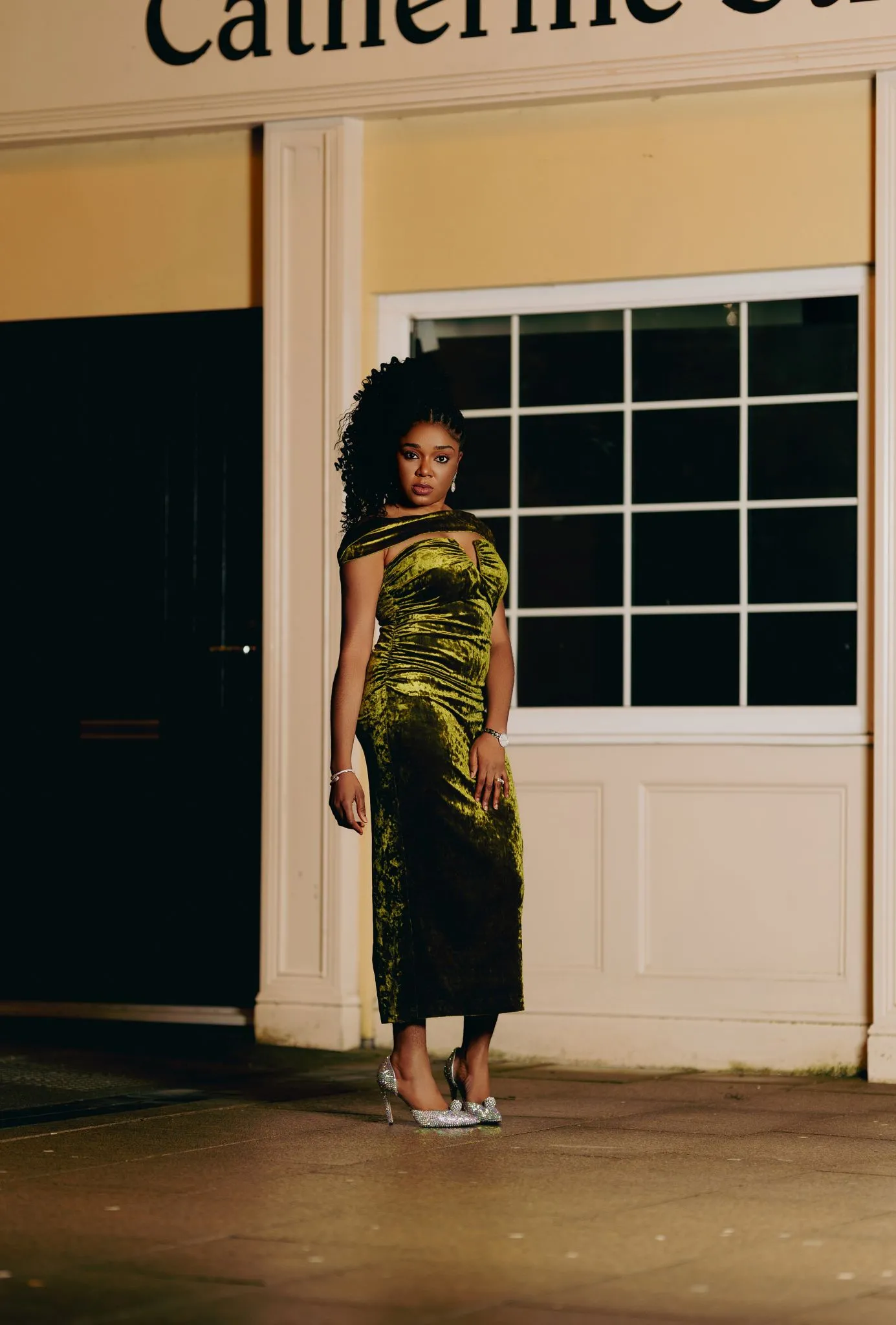 Elegant woman in a velvet evening dress standing outside a building.