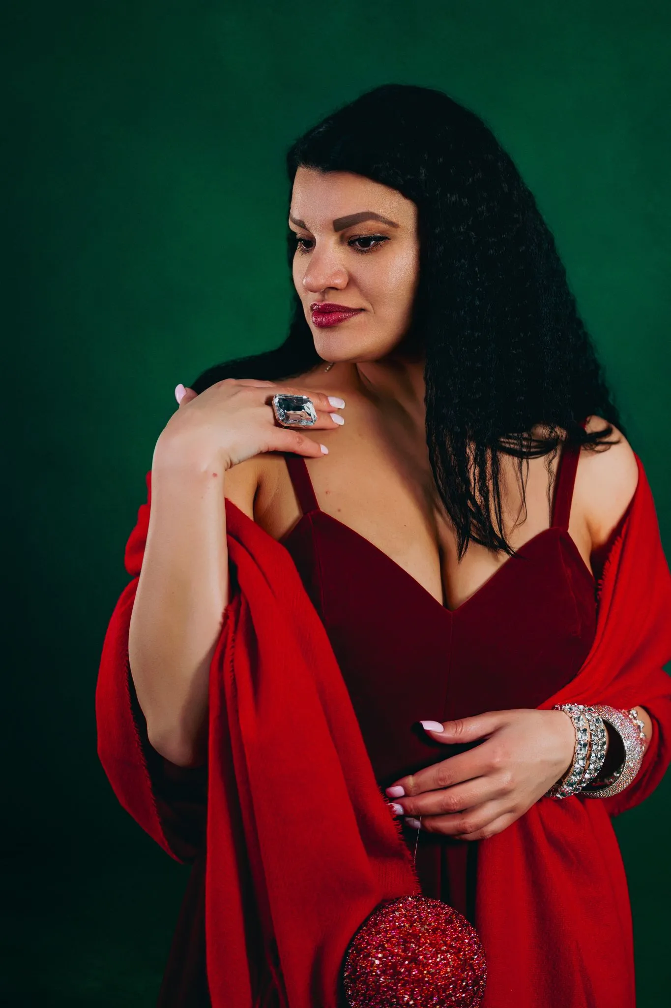 Elegant woman in a red dress with jewelry against a green background