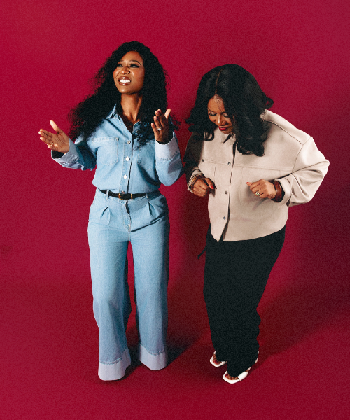 Two women dancing together against a bright red studio background