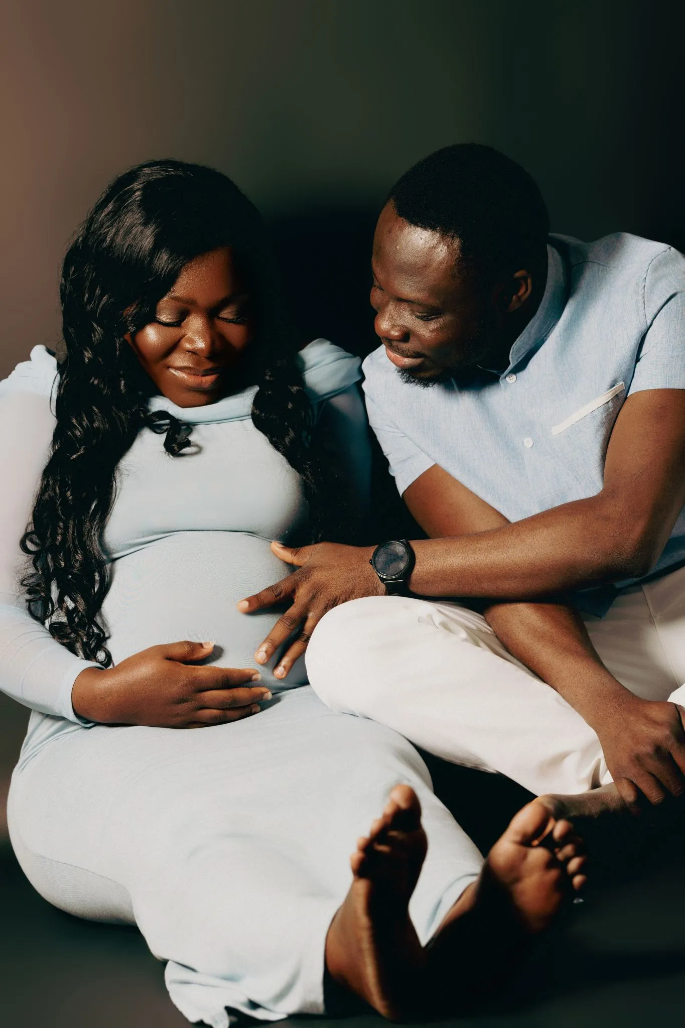 Expecting parents smiling and touching baby bump.