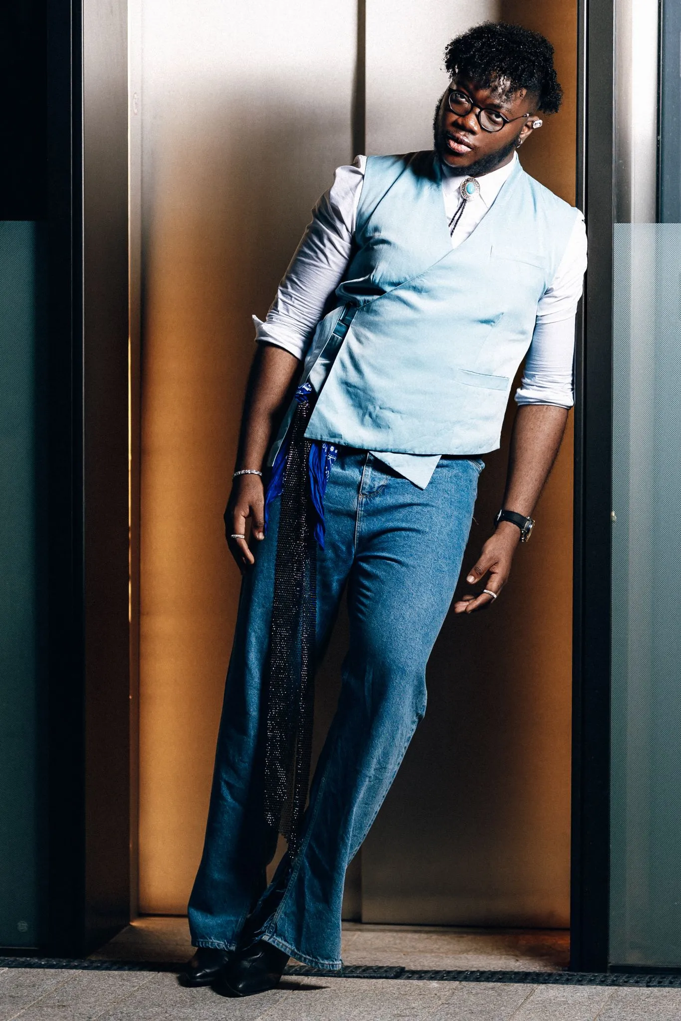 Fashionable man posing in stylish outfit with blue vest and jeans