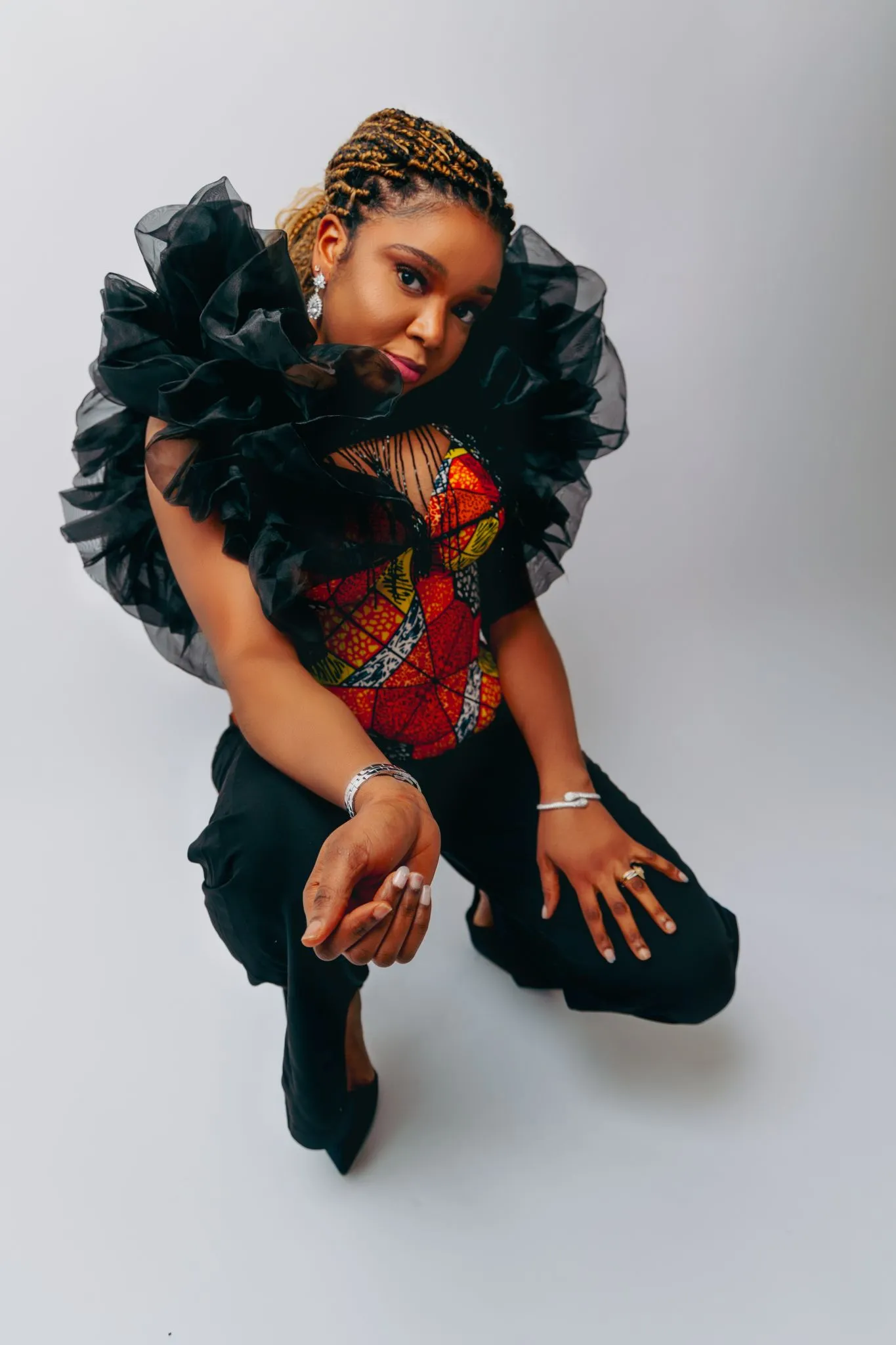 Fashionable modern portrait of a woman in a colorful outfit with ruffled black sleeves.