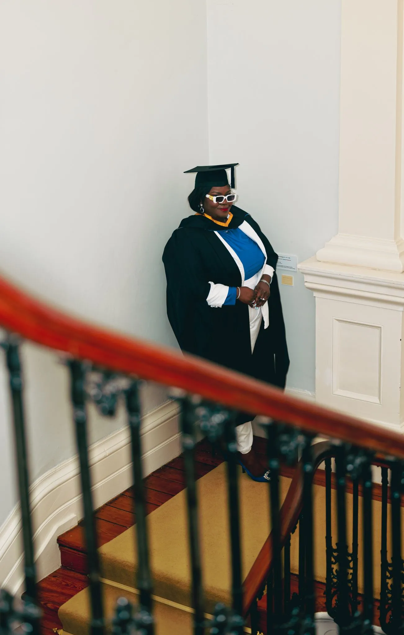 Graduate in cap and gown standing on stairs at Eagle ceremony.