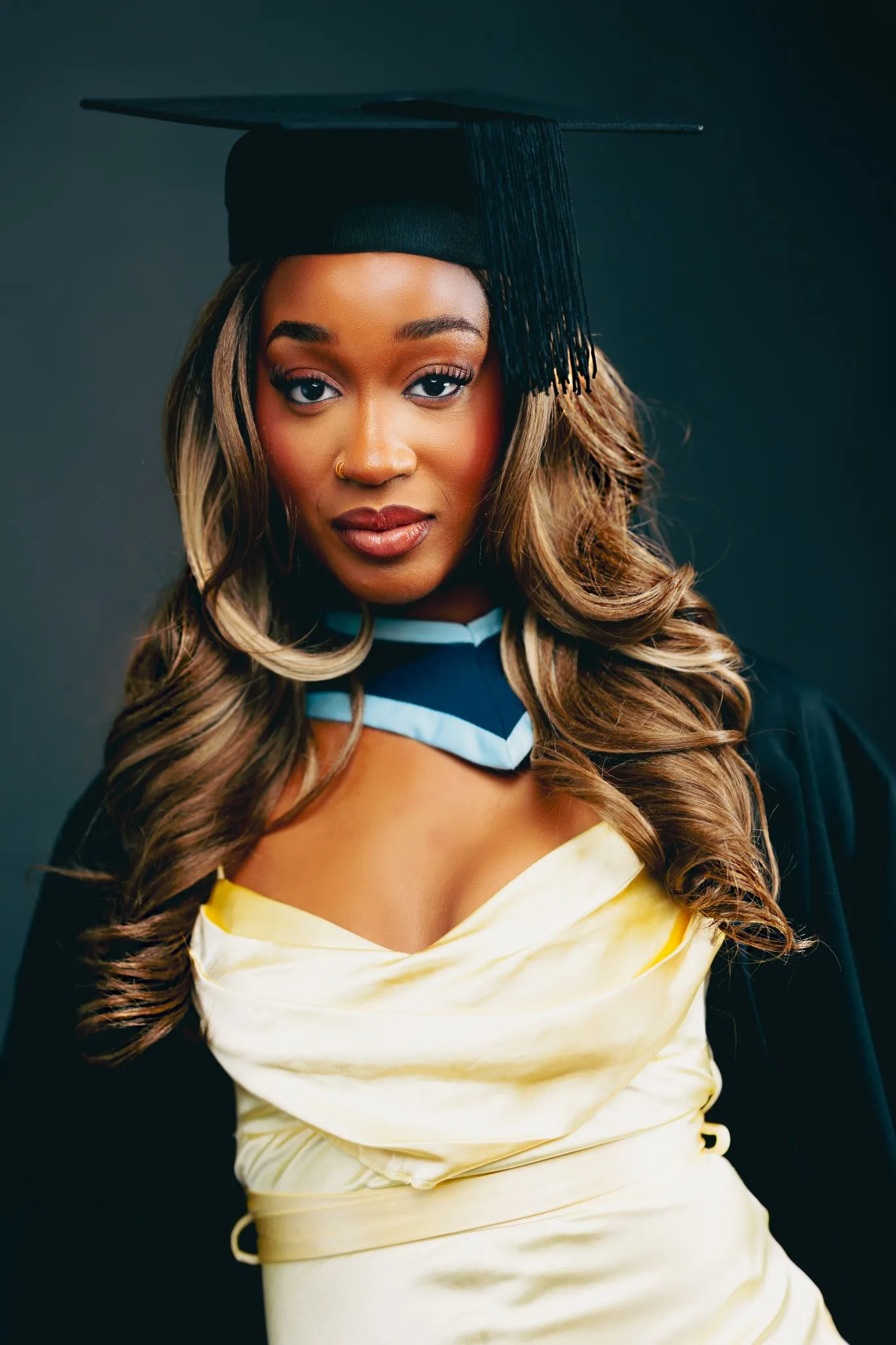 Graduate smiling in cap and gown, Eagle website.