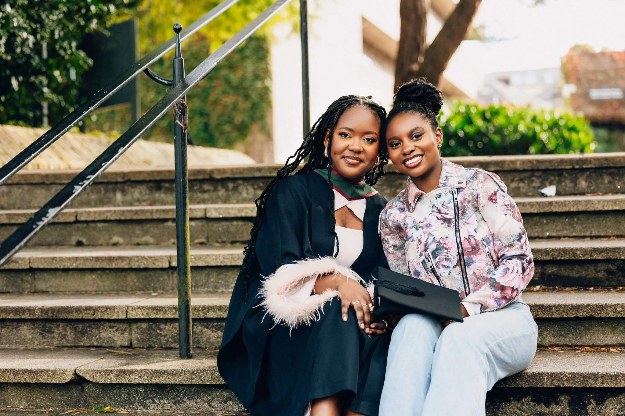 Graduation celebration with friends on steps, smiling and holding a cap.