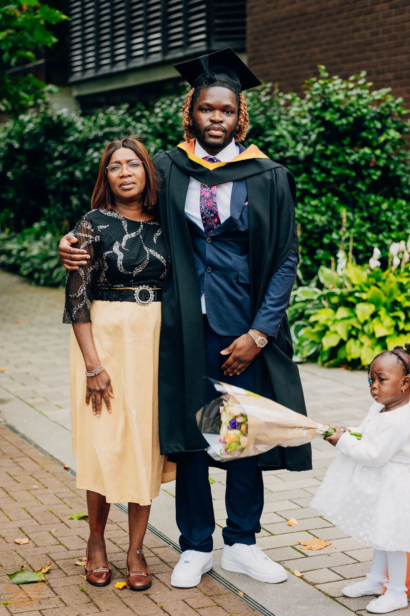 Graduate in cap and gown with family celebrating outdoors