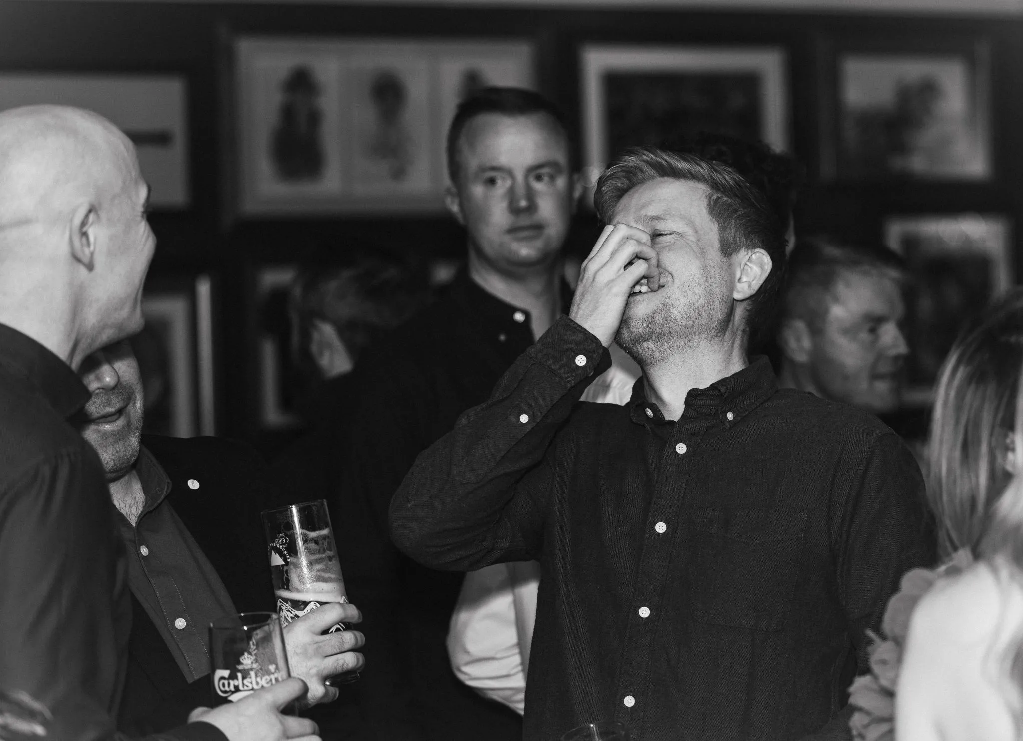 Group of people laughing at an event, enjoying drinks.