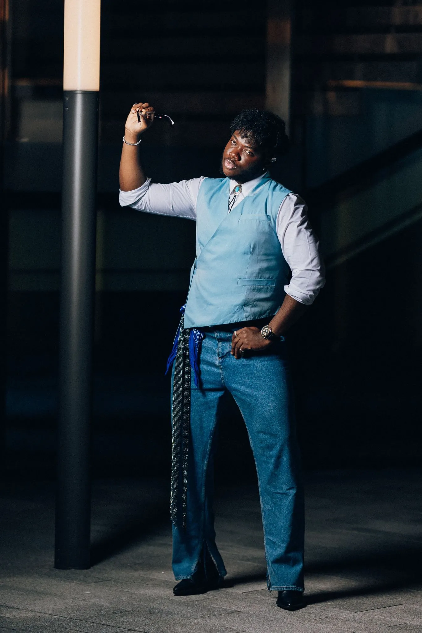 Man in blue vest posing confidently at night