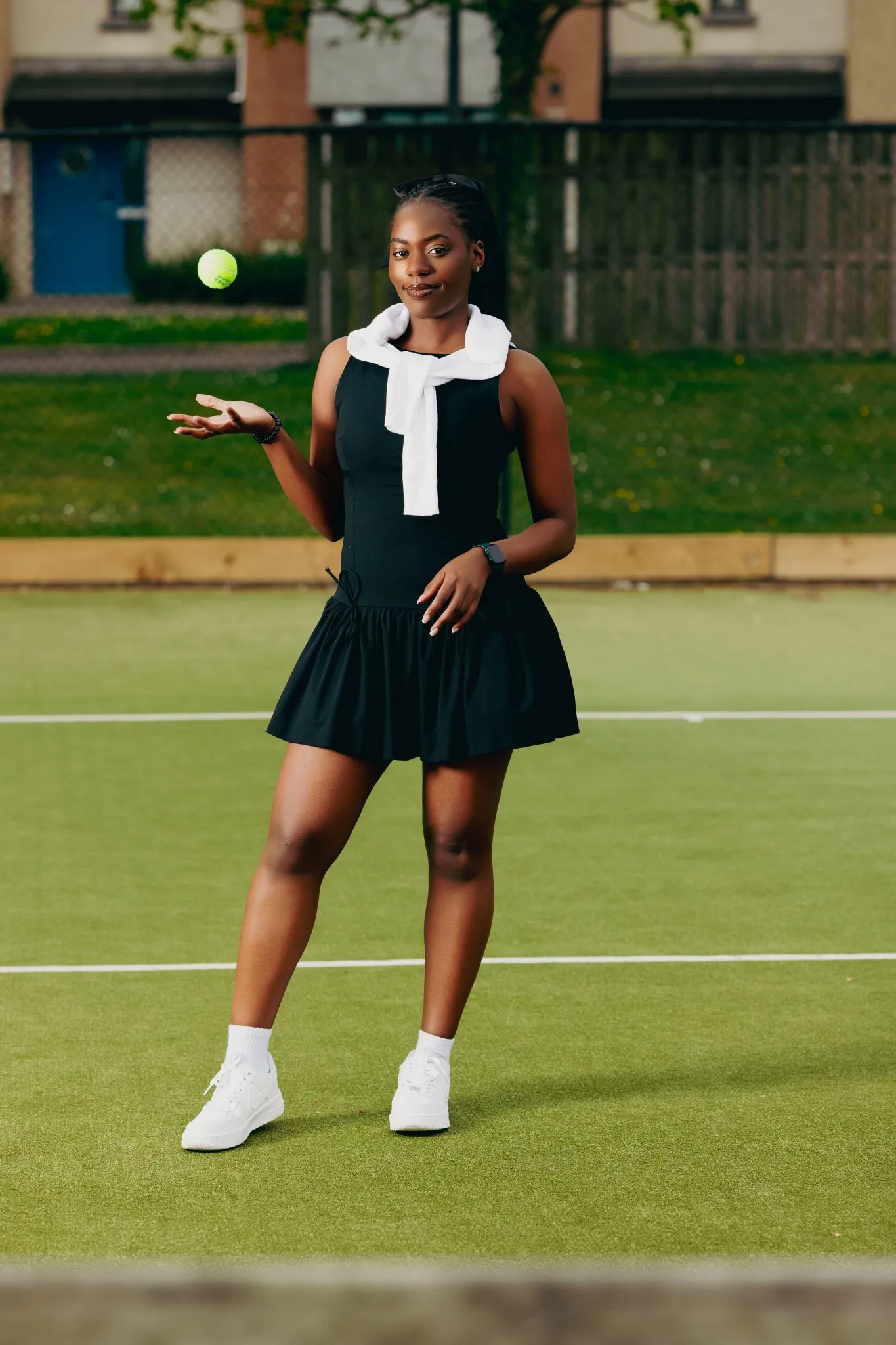 Tennis player on court in black dress with white towel
