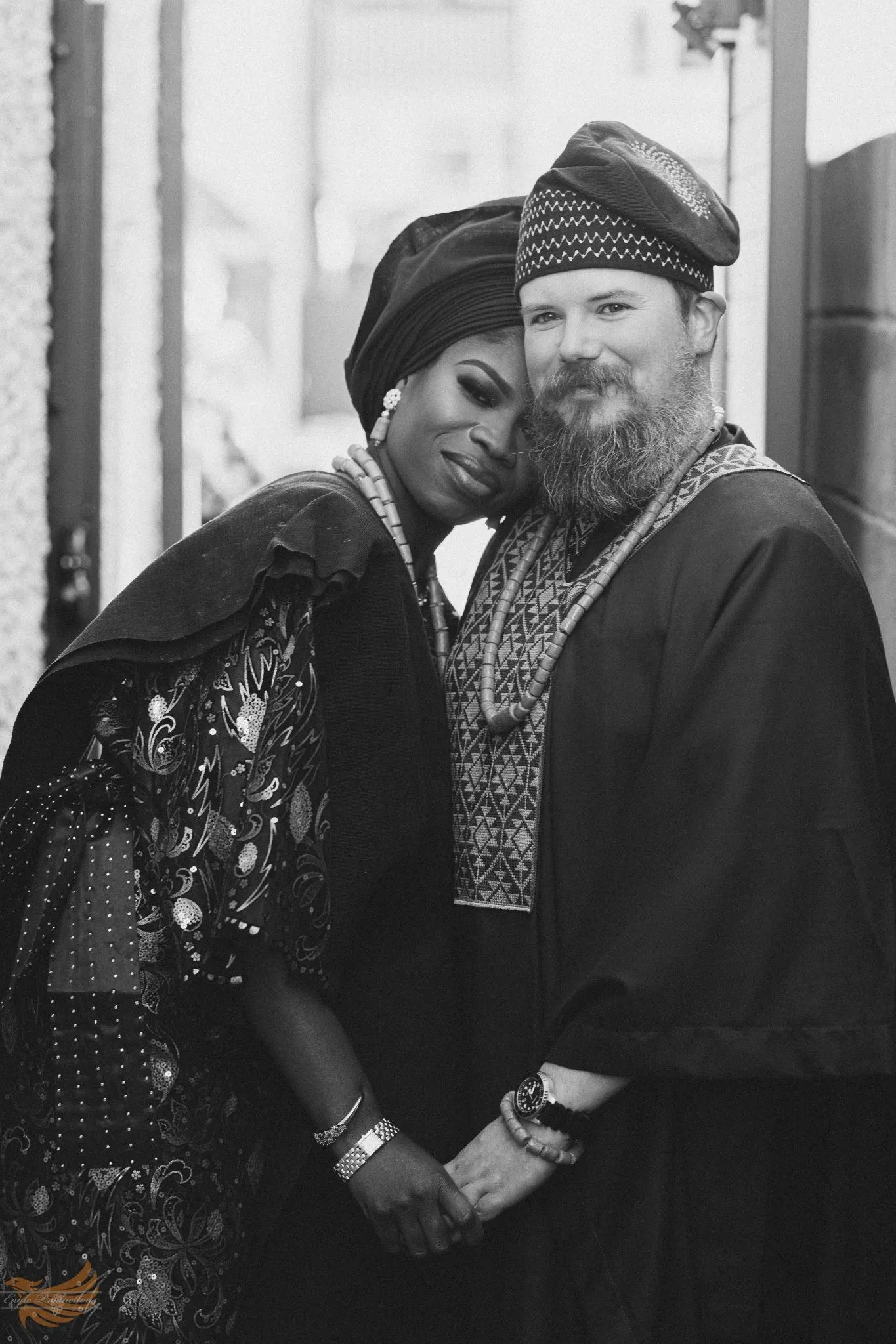 Traditional wedding couple in cultural attire, smiling and holding hands.
