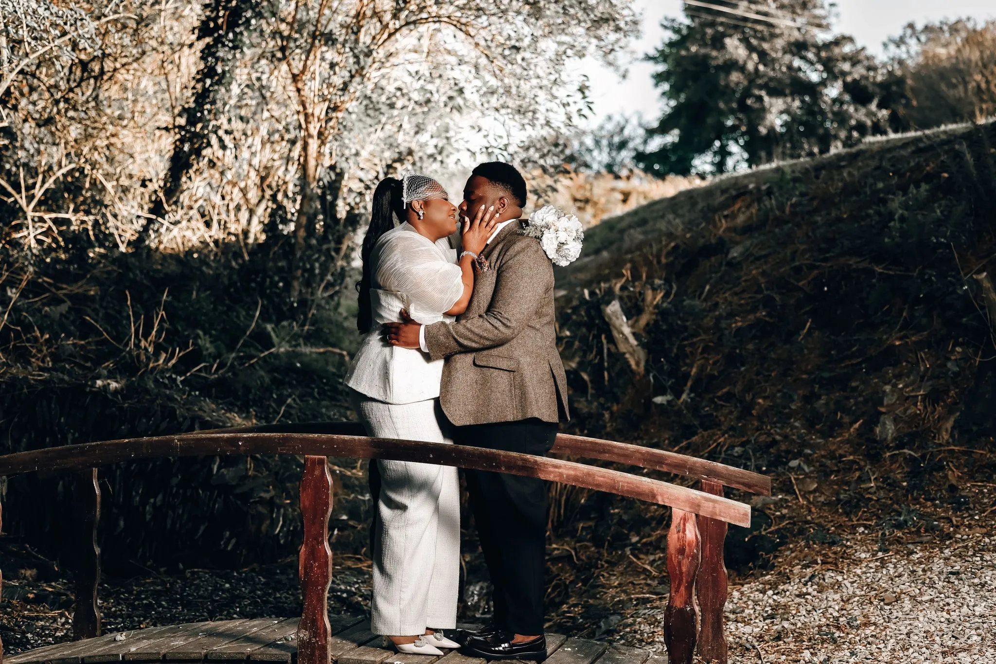 Wedding couple embracing on a rustic bridge surrounded by nature