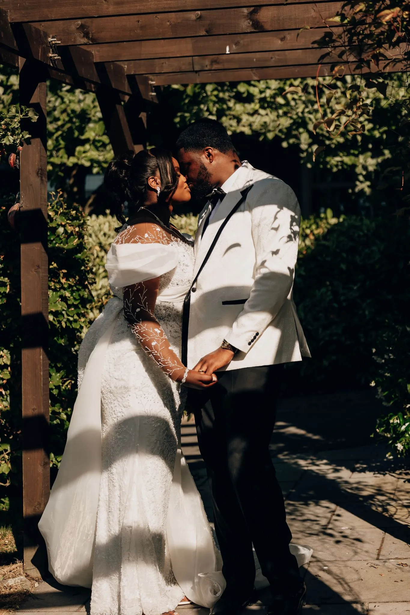 Wedding couple kissing under a wooden archway