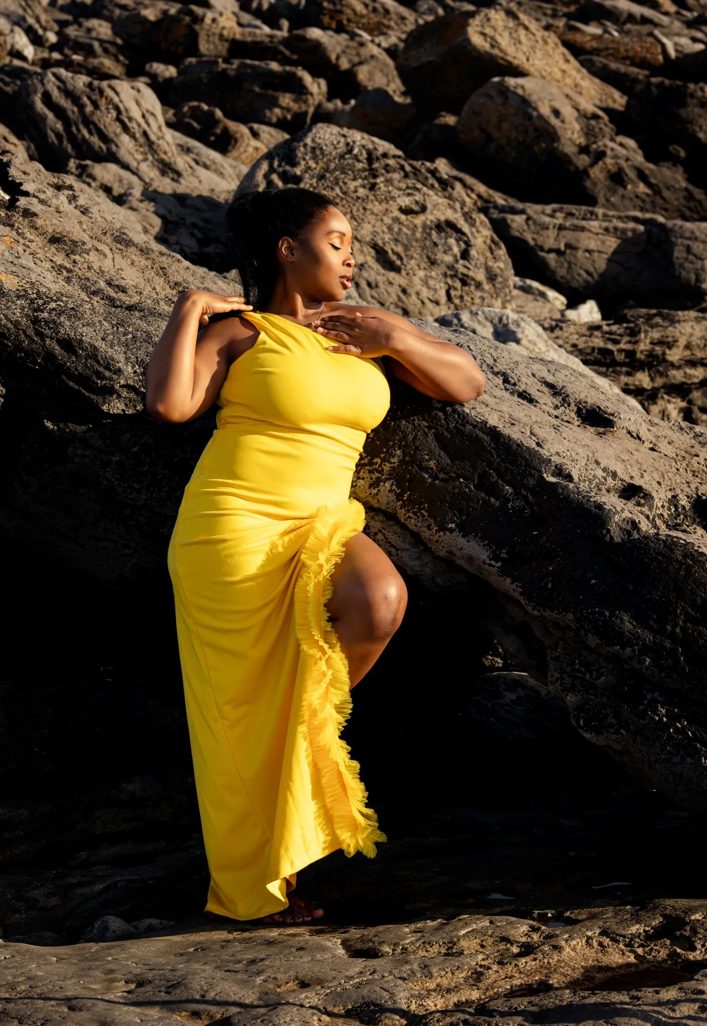 Woman in a yellow dress posing on rocky terrain